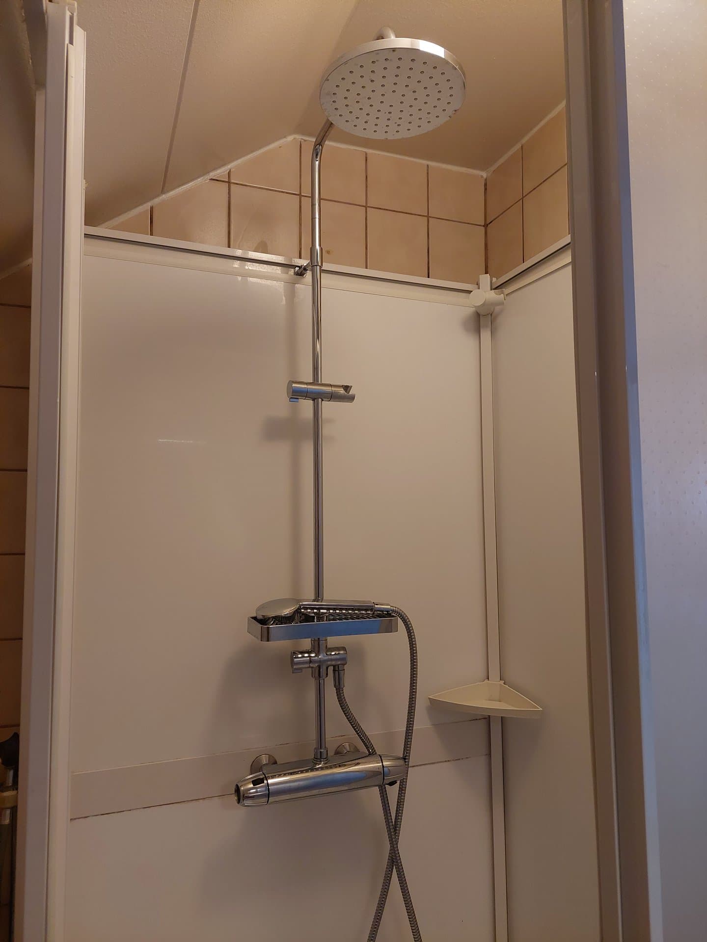 Duschhörna med takduschhuvud, handdusch och termostatblandare i krom. Praktisk hylla för schampo och tvål samt en extra hörnhylla gör det enkelt att ha allt till hands under duschen.